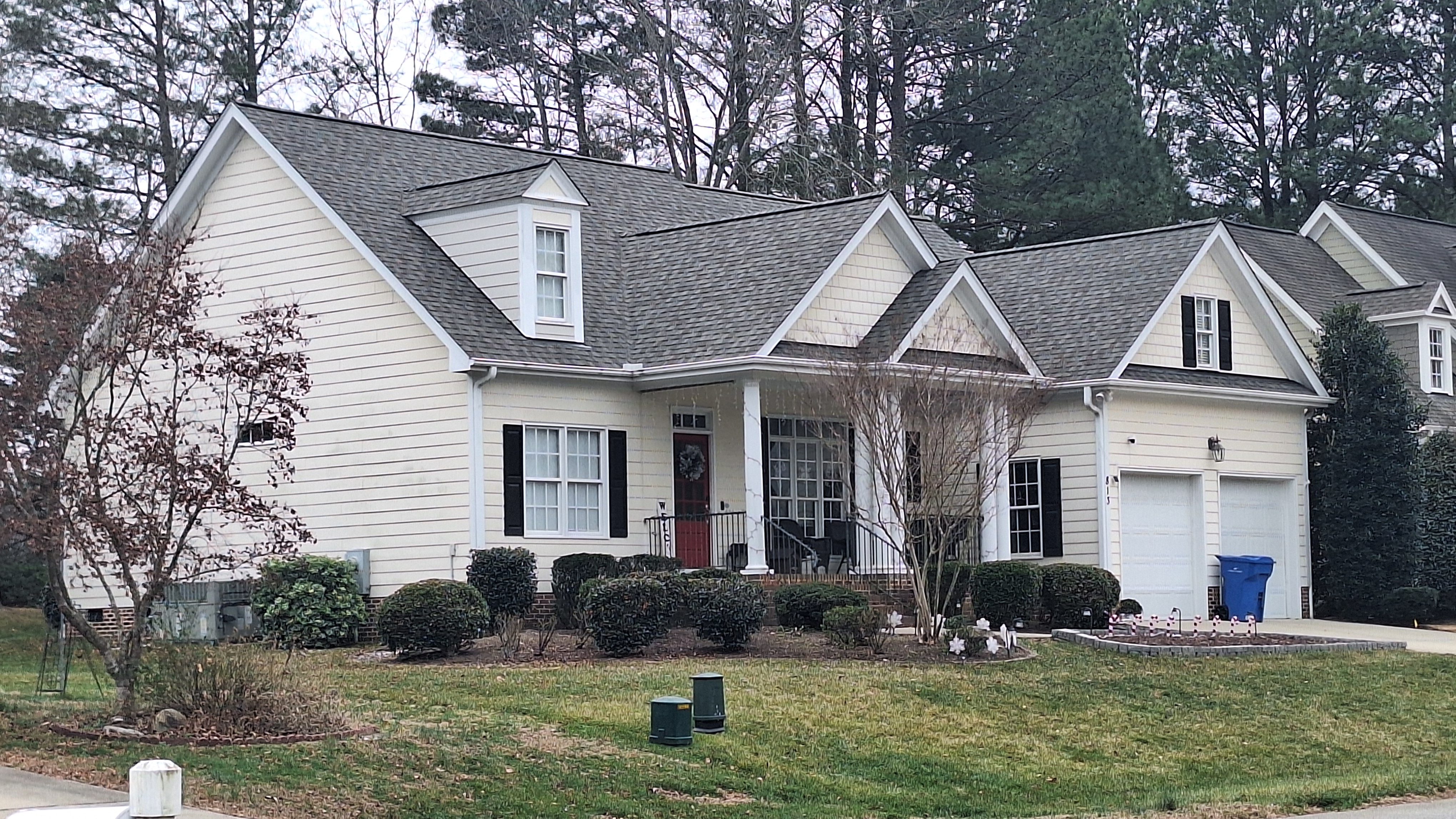 Two-story suburban house with white siding, black shutters, and two-car garage